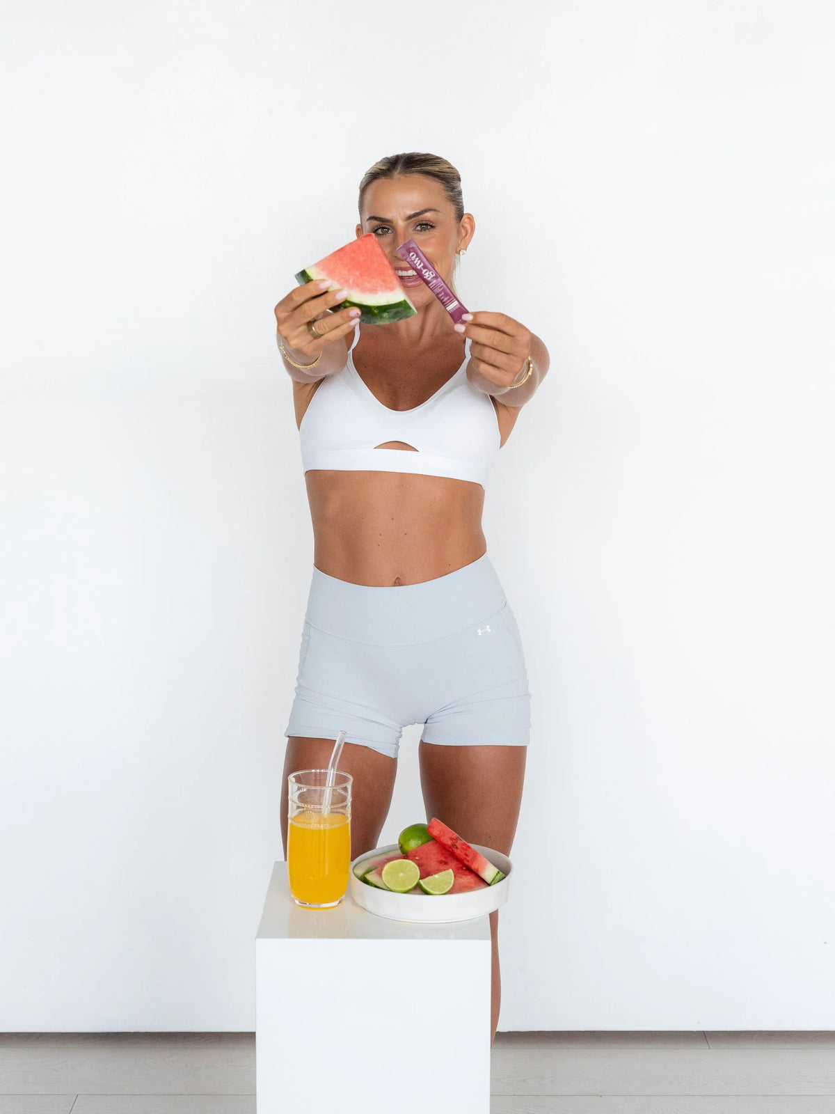 Woman holding a Go-Two Debloat stick and watermelon