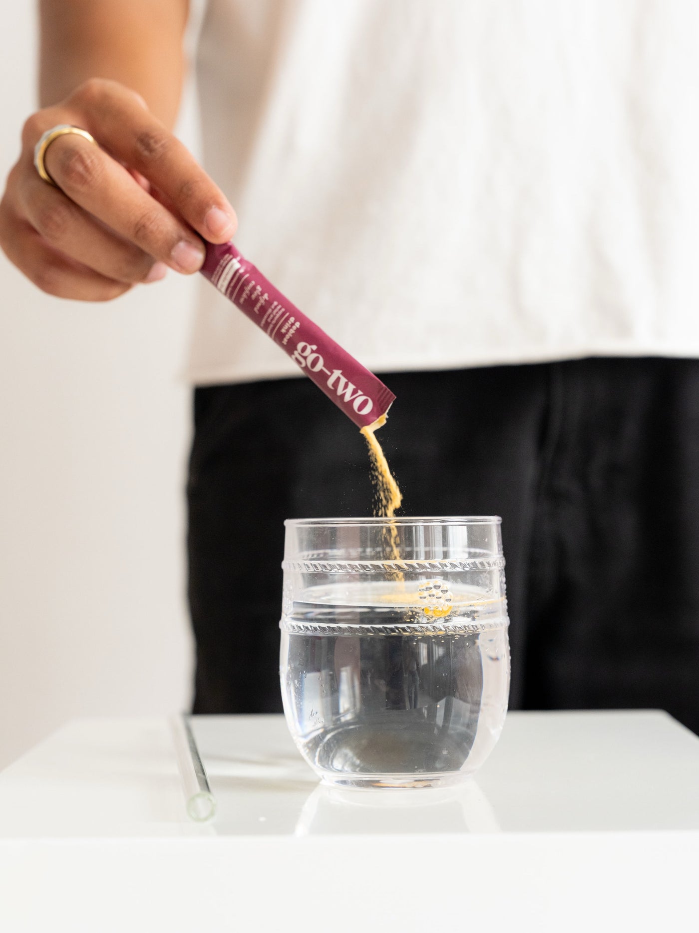 Pouring a Go-Two Debloat stick pack into a glass of water