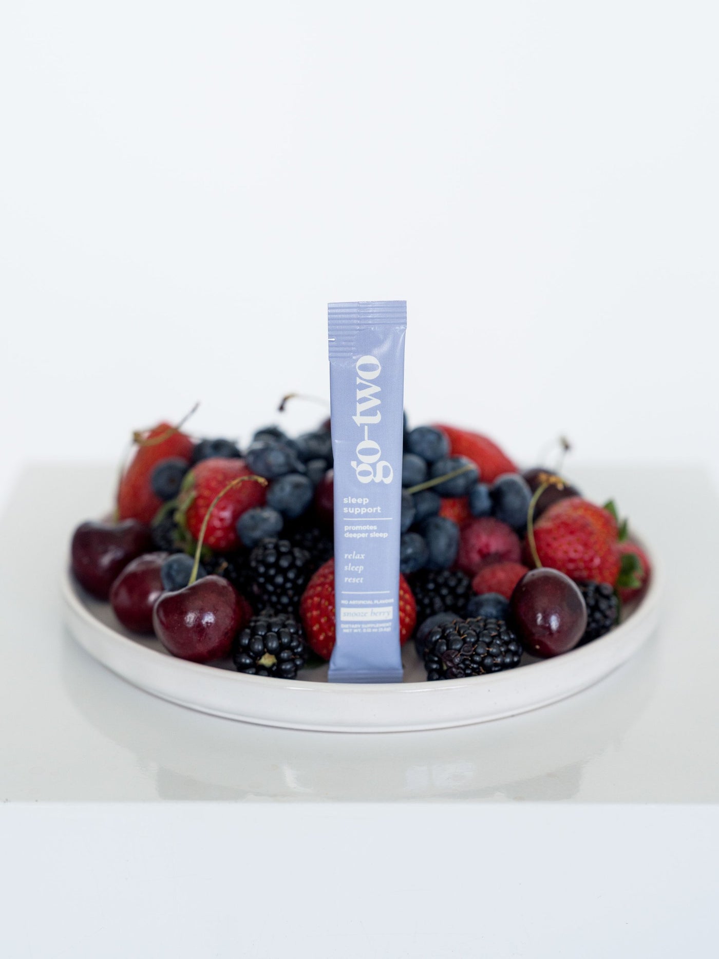 Go-Two Sleep Support stick pack standing in a bowl of fresh berries and cherries