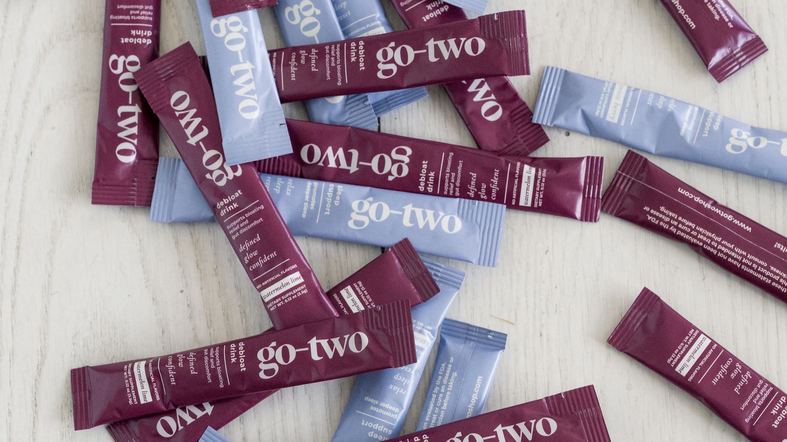 Go-Two Debloat and Sleep Support stick packs scattered across a white wood surface