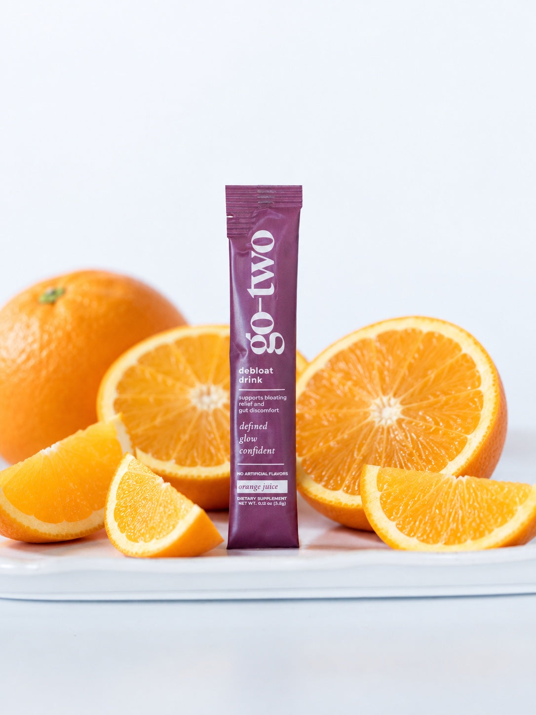 Orange Juice Debloat product image with a purple stick pack and fruit
